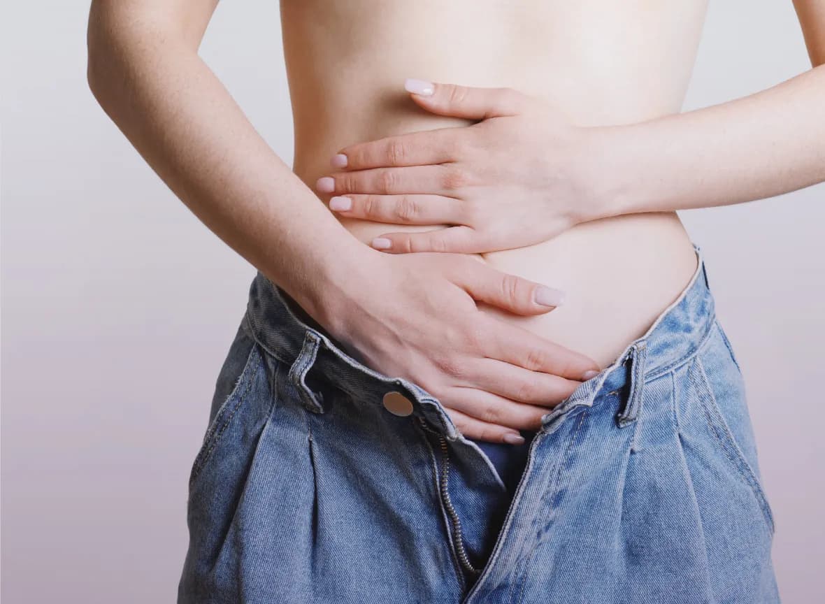 Mujer con las manos sobre la parte baja del abdomen