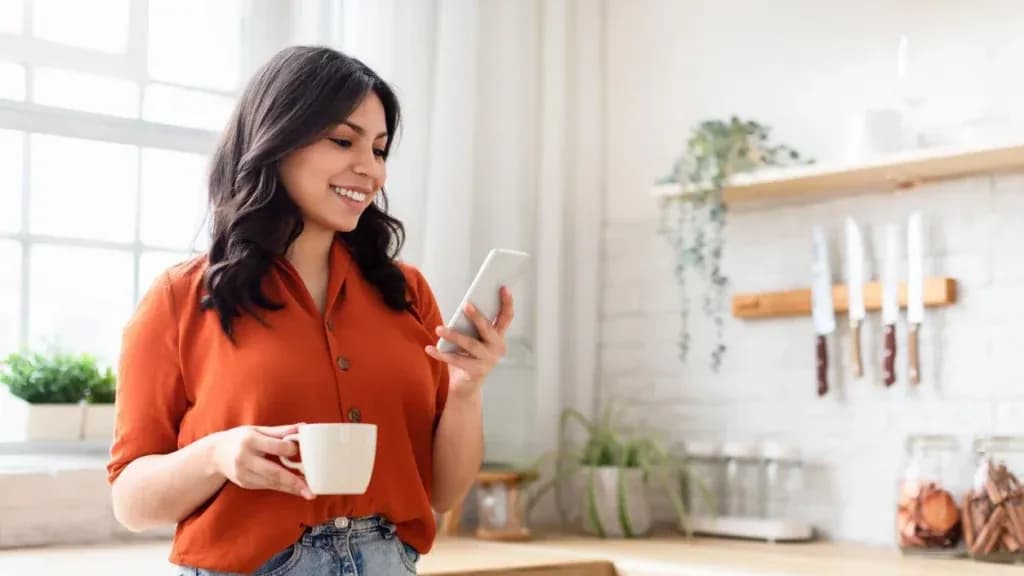 Mujer leyendo un mensaje en su teléfono en casa